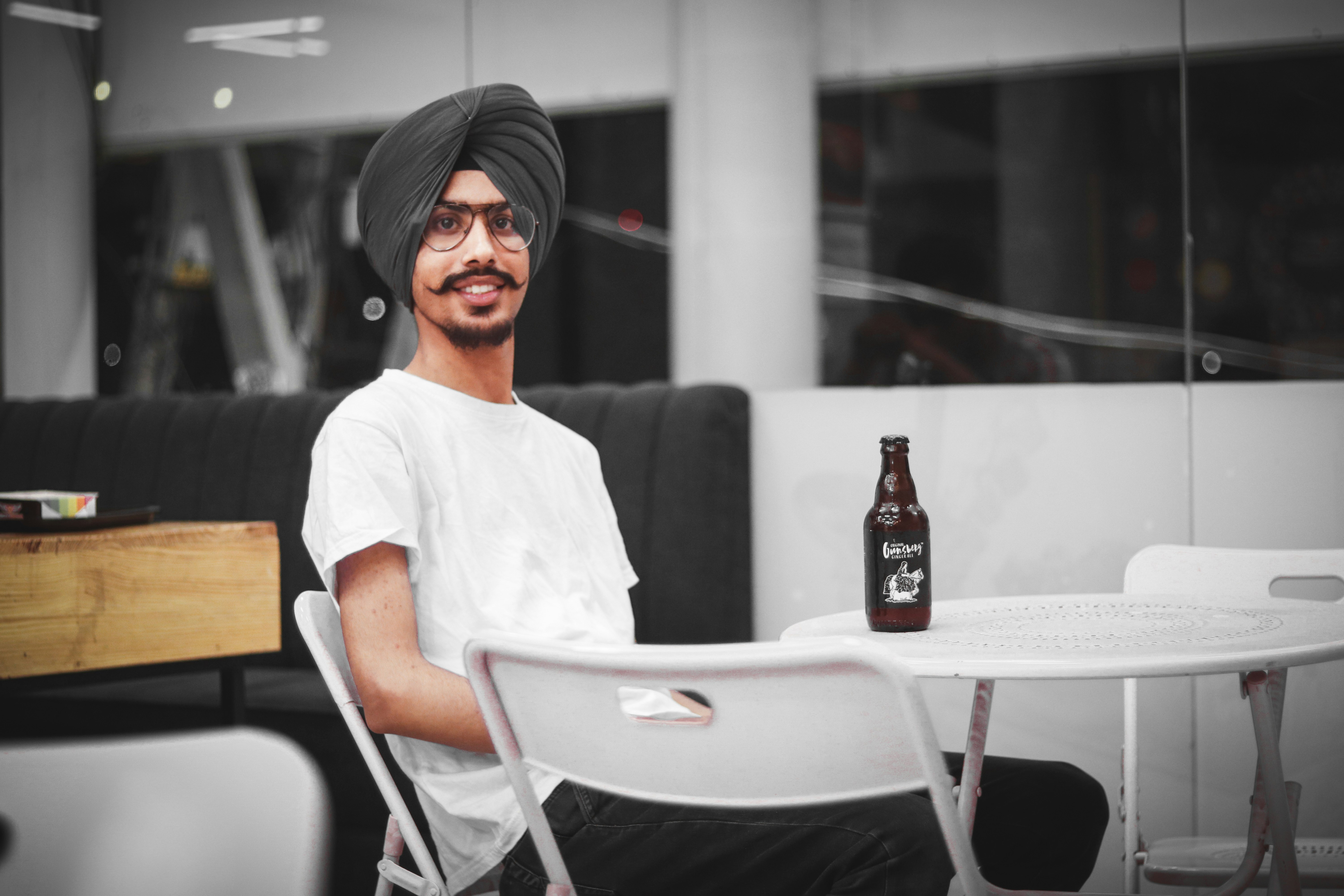 man sitting on chair near table with bottle of beer